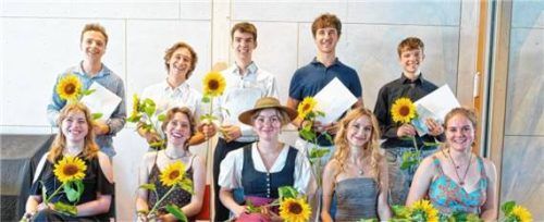 Die zehn Absolventinnen und Absolventen des Abiturjahrgangs 2026 der Freien Waldorfschule Rosenheim posieren mit ihren Zeugnissen und Sonnenblumen. Foto Martin Schön