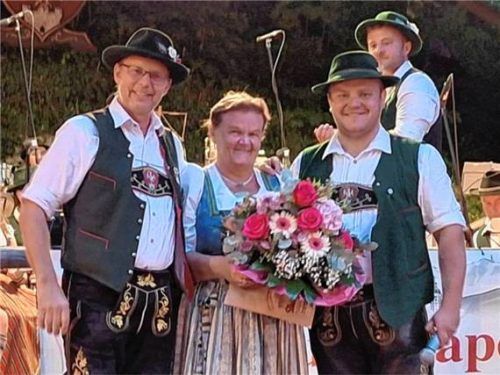 Ehrung beim Waldfest in Flintsbach: Alex Schirmann (links) und Tomi Astner überreichen Michaela Goldes einen Blumenstrauß. Foto 2026 OVB