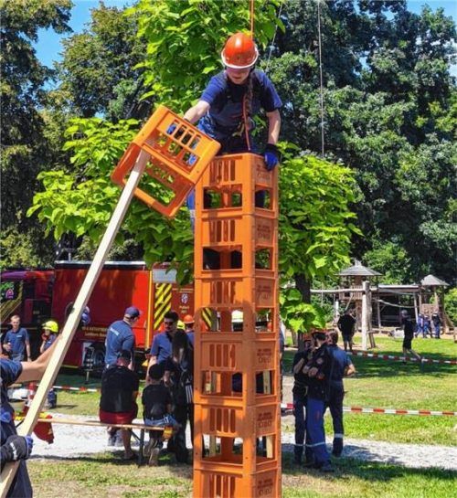 Eine Jugendliche stapelt Kisten in die Höhe, während sie gesichert ist. Foto Kreisfeuerwehrverband Rosenheim