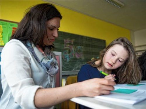 Eine Schülerin mit Down-Syndrom sitzt im Schulunterricht neben einer Schulassistentin. Foto dpa