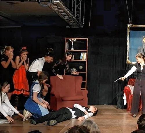 Eine Szene aus dem Theaterstück „Mörder auf Schloss Edelstein“ mit mehreren Darstellern auf der Bühne. Foto Inntal-Gymnasium Raubling