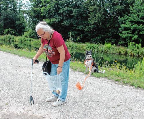 Hund Sedi wartet geduldig, während Renate Carta aus Kolbermoor mit ihrer Greifzange auf der Gassirunde Müll aufsammelt. Foto Riediger