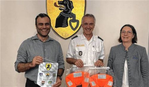Bürgermeister Alois Loferer (links) und Ferienprogrammverantwortliche Steffi Mühlnickel-Rieder (rechts) überreichen Jürgen Thalmeier (Mitte), Leiter der Polizeiinspektion Prien, zwei Schwimmwesten als Dank für das Engagement im Ferienprogramm. Foto  Ammelburger