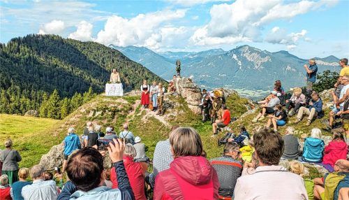 Eine große Gruppe von Gläubigen versammelt sich zur Bergmesse auf der Jochbergalm mit Pfarrer Klaus Wernberger am Altar und Musikern im Hintergrund. Foto Flug