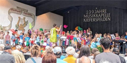 Mit dem Elan der Jugend: Kinder auf der Bühne der Musikkapelle Kiefersfelden schwenken bunte Tücher und begeistern das Publikum bei der Sommermatinee. Foto Hoffmann