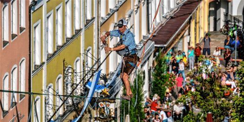 Balance und Bier: Friedi Kühne schenkte auf der Highline über dem Traunsteiner Stadtplatz am vergangenen Samstag in schwindelerregender Höhe ein alkoholfreies Bier ein. Unten verfolgen die Zuschauer jeden Schritt und zitterten mit. Nitzsche