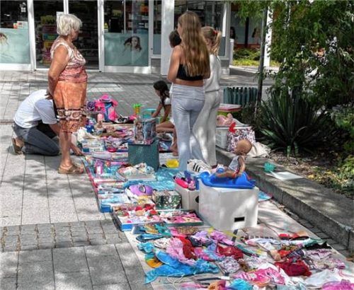 Kinder und Erwachsene stöbern auf dem Kinderflohmarkt des Seniorenbeirats in Waldkraiburg, wo Spielsachen und Kleidung zum Verkauf angeboten werden. Seniorenbeirat