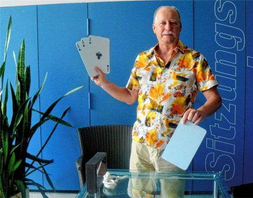Michael Lode präsentiert verschiedene Trick-Materialien, darunter große Spielkarten.  Fischer
