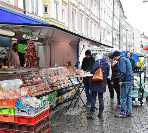 Besucher informieren sich an einem Imbiss- und Feinkoststand über das Angebot. Schlecker