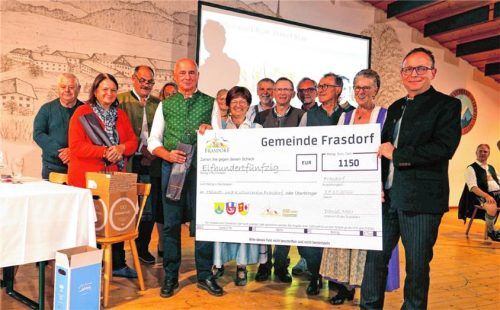 Bürgermeister Daniel Mair (rechts) übergibt einen Symbol-Scheck über 1.150 Euro an den Heimat- und Kulturverein Frasdorf. Hötzelsperger