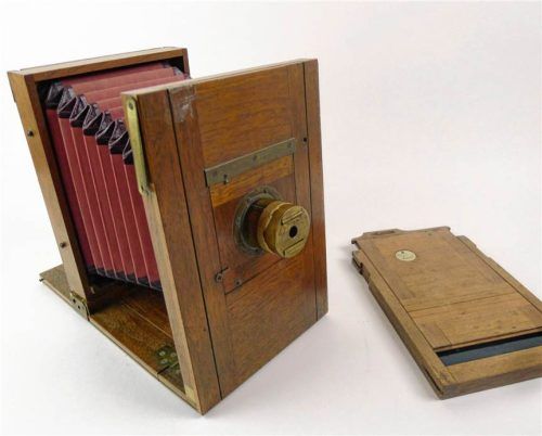 Die historische Plattenkamera aus Holz mit rotem Balg und einer dazugehörigen Kassette für Glasplatten. Städtisches Museum Rosenheim