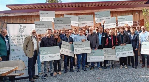 Die Teilnehmer des zehnten Netzwerktreffens des Klimaschutznetzwerks Rosenheim-Traunstein präsentieren Schilder ihrer Kommunen. Institut für nachhaltige Energieversorgung GmbH