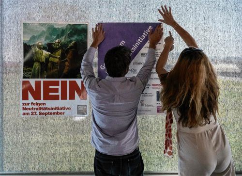 Zwei Mitarbeiter einer Kommunikationsagentur kleben Abstimmungsplakate an die Scheiben des überparteilichen Nein-Komitees gegen die Neutralitätsinitiative, über die Volk und Stände in der Schweiz entschieden haben. dpa